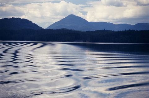 usa, alaska, prince of wales island, water patterns in foreground with shore and mountain in background