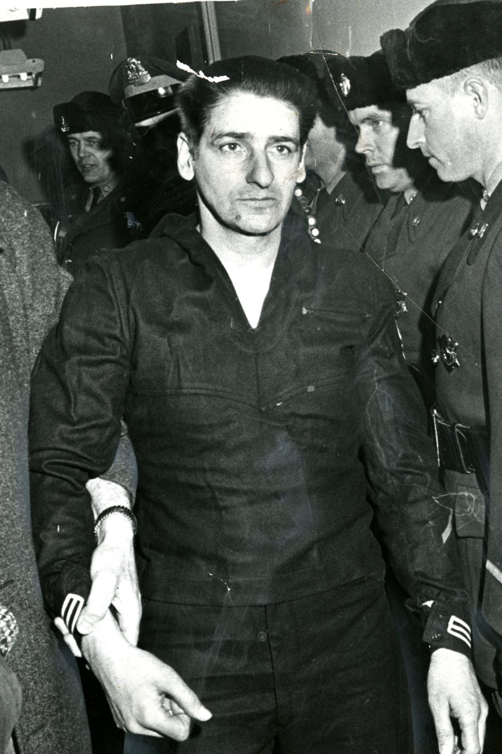 albert desalvo being held at the wrist by another person as he walks forward