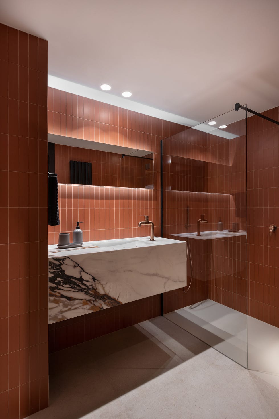 baño con azulejos en color teja y mueble volado de mármol