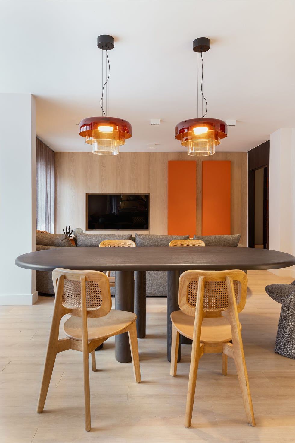 mesa de comedor ovalada con sillas de madera y lámparas suspendidas