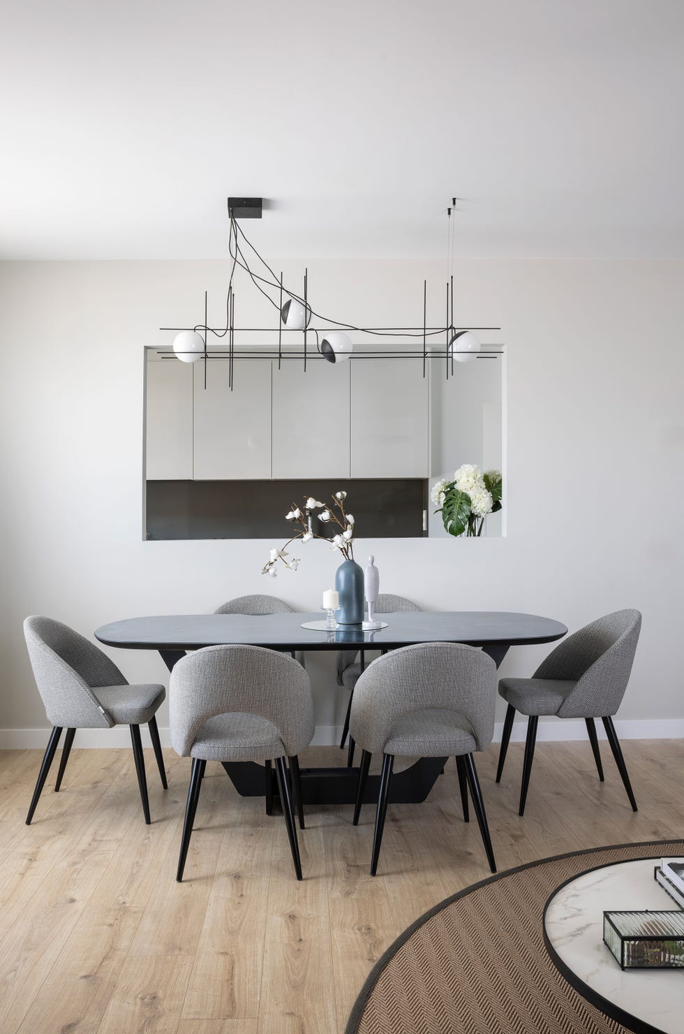 mesa de comedor ovalada con sillas grises y lámpara suspendida