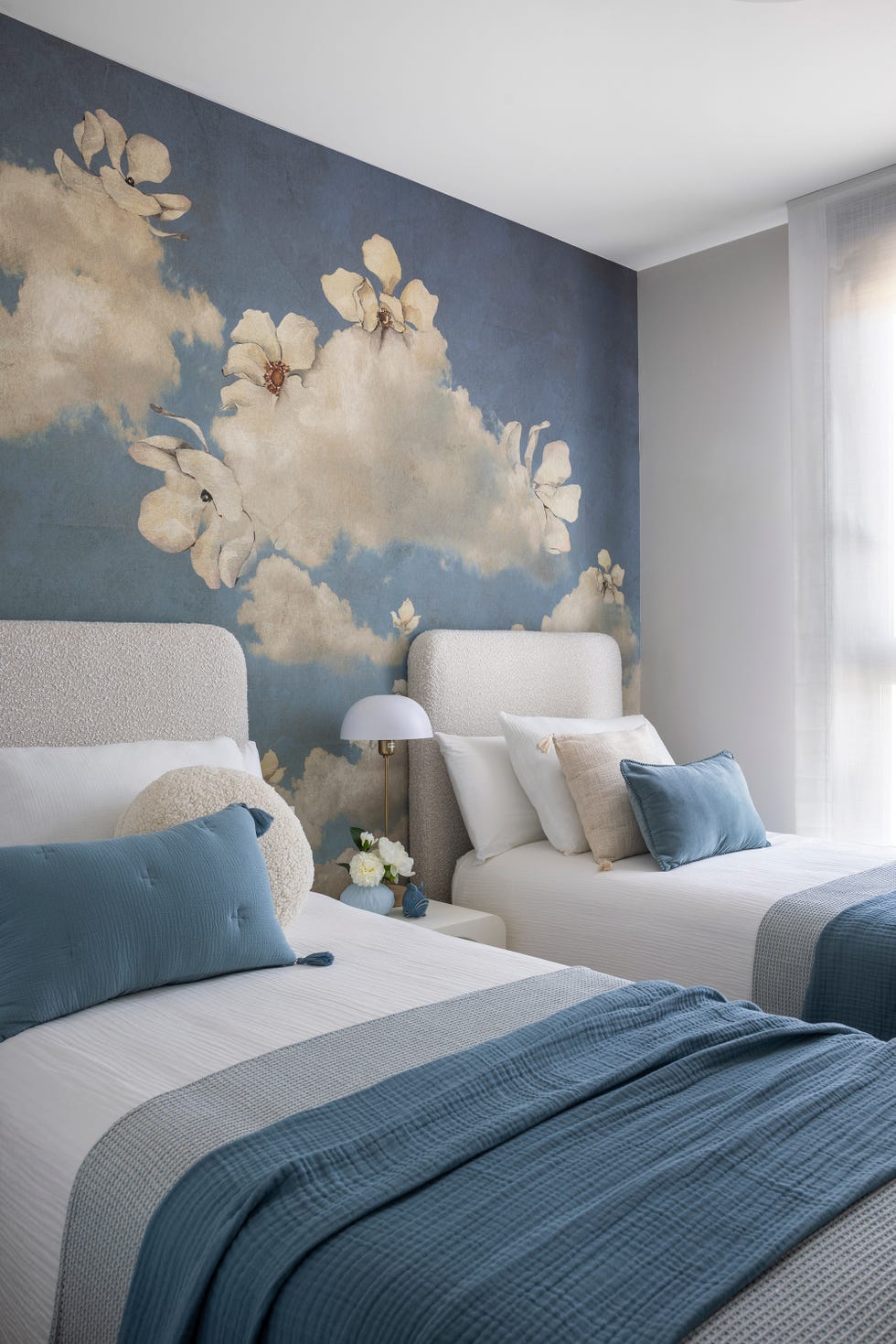 habitación con dos camas con cabeceros bouclé y papel pintado con motivos florales azul