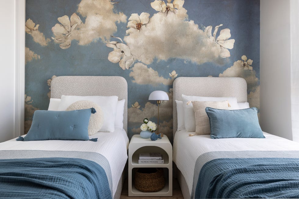dormitorio infantil con dos camas y cabeceros bouclé y papel pintado con motivos florales azul