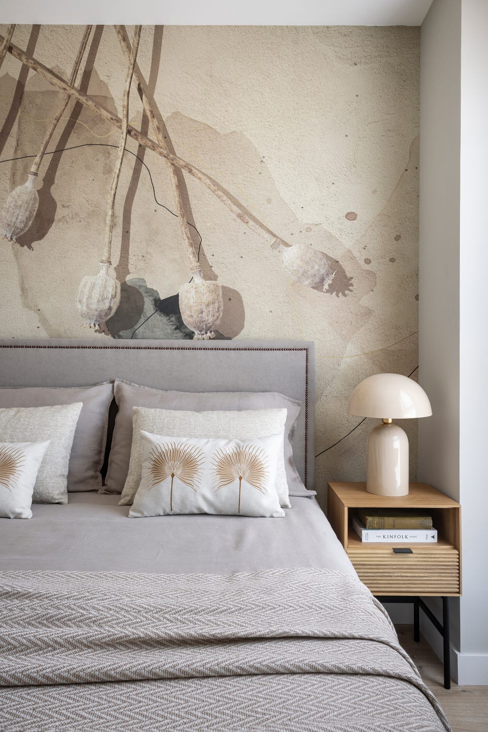cabecero gris con remaches, mesita de madera y papel pintado con motivos florales