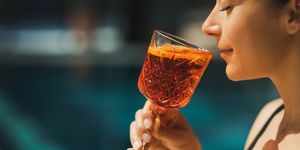 woman drinking aperol spritz by the pool
