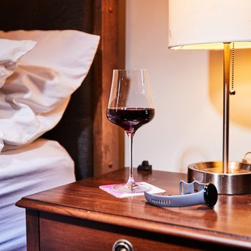 a glass of wine on a bedside tveis with a fitness watch next to it
