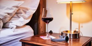 a glass of wine on a bedside table with a fitness watch next to it