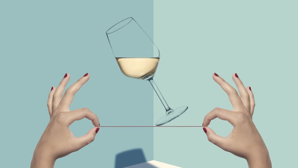 mani che tengono un filo con sopra un bicchiere di vino