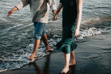 a man and woman holding hands on a beach