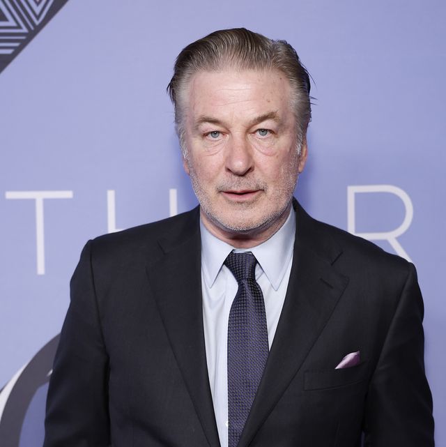 alec baldwin wearing a suit jacket and tie posing for a photograph
