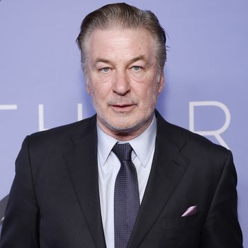 alec baldwin wearing a suit jacket and tie and posing for a photo