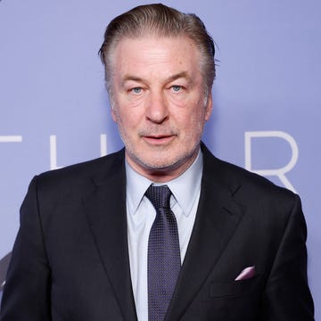 alec baldwin wearing a suit jacket and tie and posing for a photo