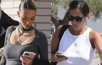 two women outdoors both holding mobile phones