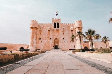 a stone building with a flag on top with lahore fort in the background