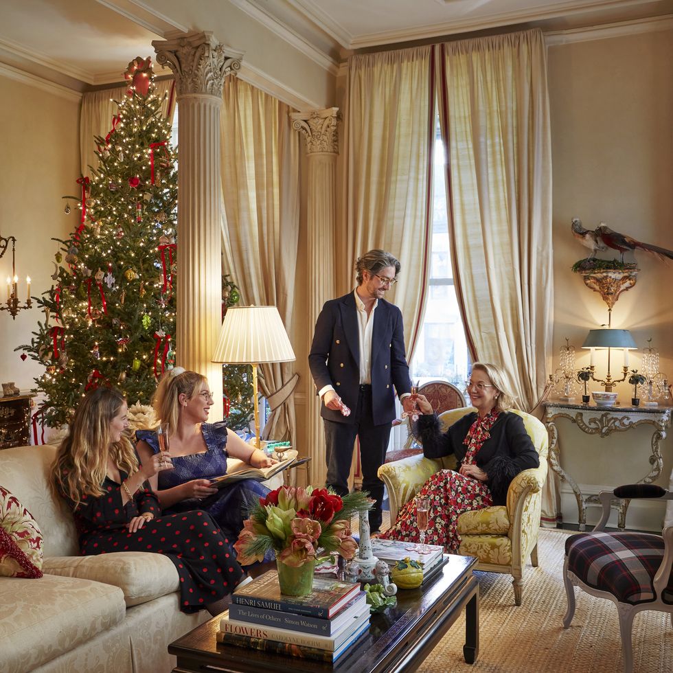 a family entertains in a living room with a christmas tree in the corner