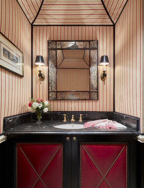 a powder room with red and white striped upholstered walls and black accents