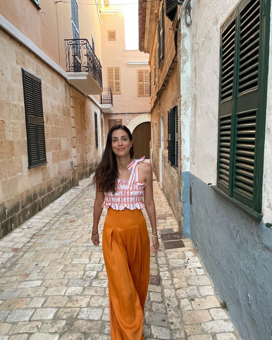 Alessandra de Osma con pantalón palazzo naranja y crop top vichy