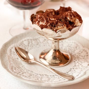 a glass of red wine with a slice of cake on top