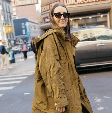 person wearing a loose olivegreen jacket with a large hood and carrying a stylish handbag person wearing a loose olivegreen jacket with a large hood and carrying a stylish handbag