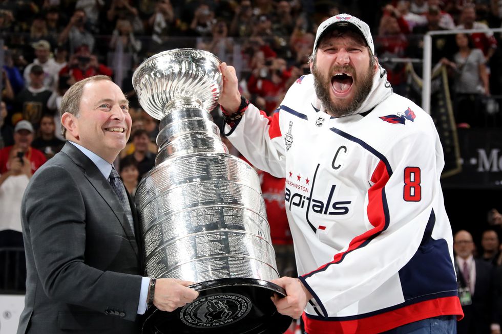alex ovechkin smiling and yelling as he takes the stanley cup from gary bettman