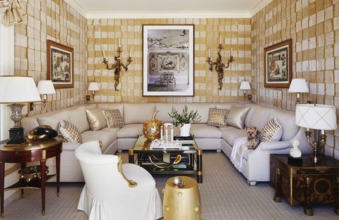 a large white sectional sofa in an ivory and gold room with gold upholstered walls