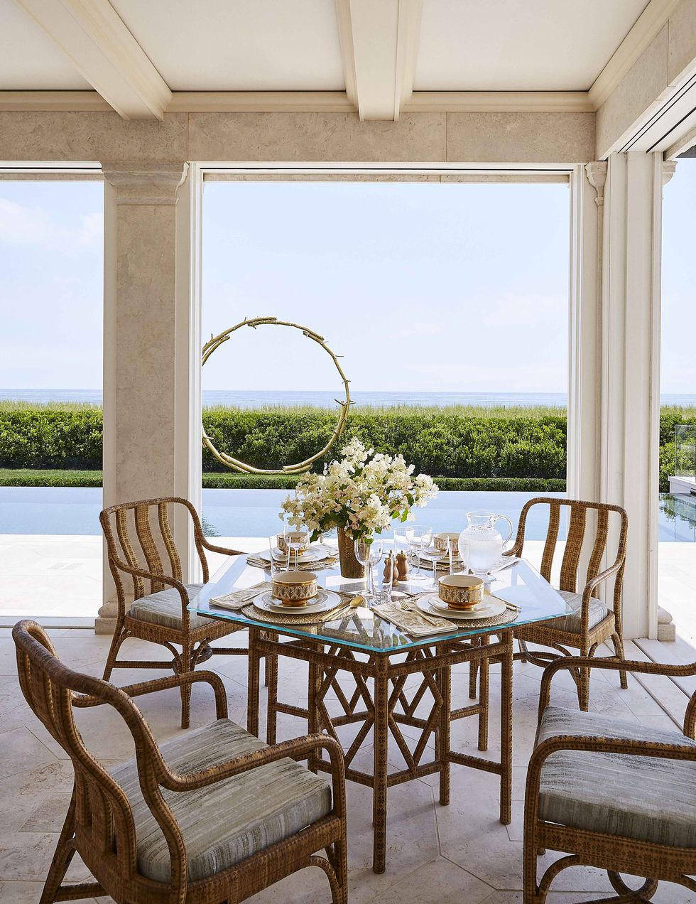 a small dining table with four chairs on a poolside terrace