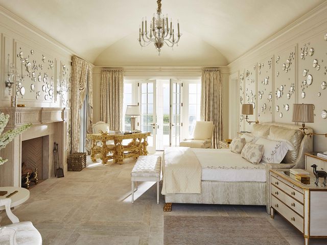 an ivory and gold master bedroom with a fireplace and large bed with doors opening out to the ocean