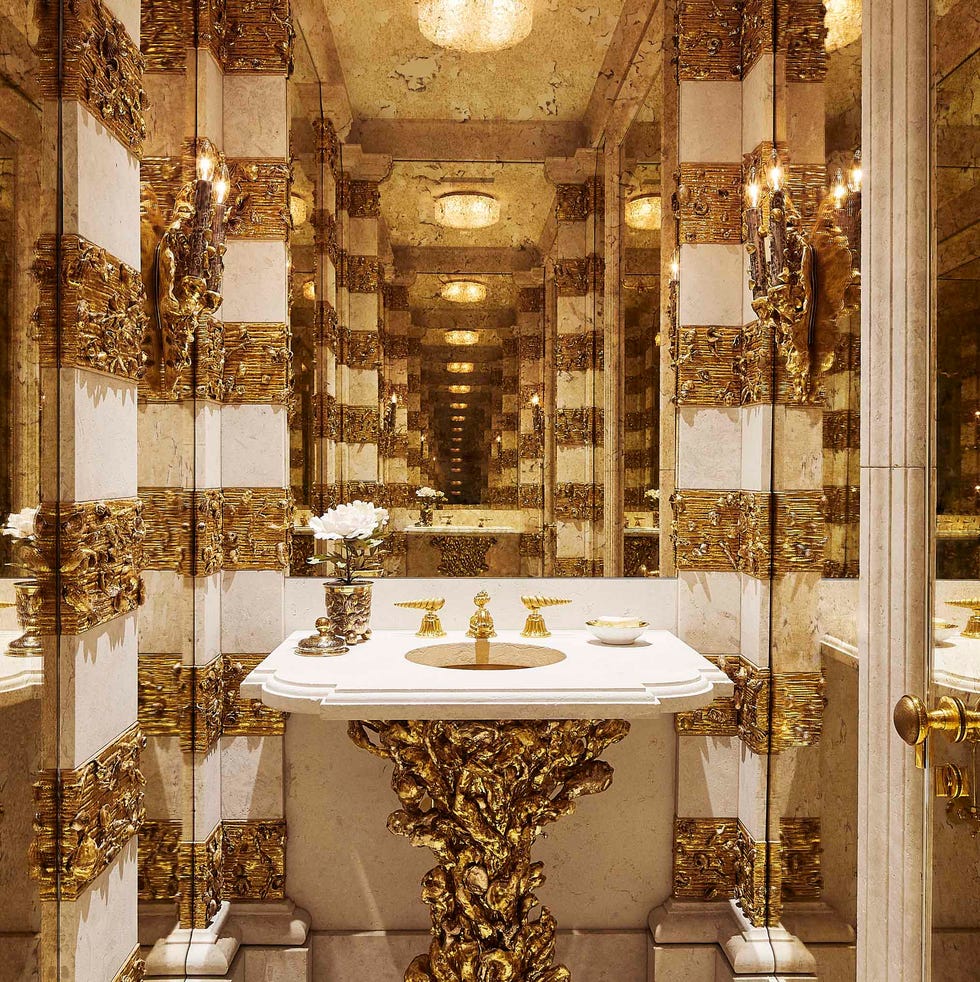 a powder room with white marble and gold details on the sink pedestal and walls