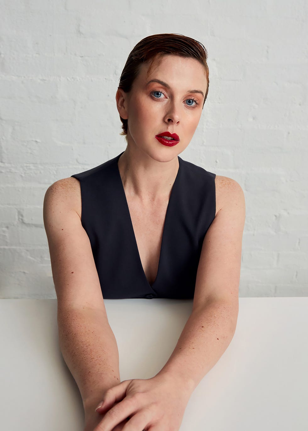 a person with folded arms wearing a sleek darkcolored outfit
