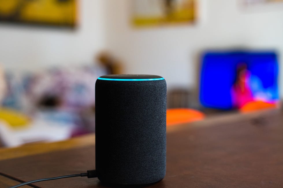 amazon alexa smart assistant device connected at home on table, defocused living room in background, no people