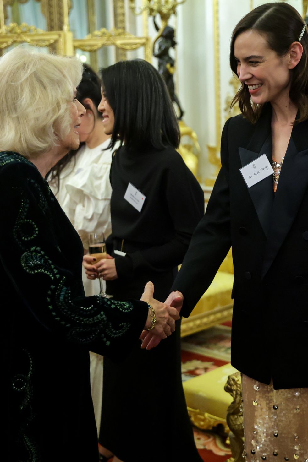 london, england february 01 camilla, queen consort shakes hands with alexa chung during a reception hosted by the king and the queen consort to celebrate british east and south east asian communities at buckingham palace on february 01, 2023 in london, england the reception is taking place shortly after lunar new year, the holiday began as a time for feasting and to honour household and heavenly deities, as well as ancestors guests include representatives of the armed forces, the arts, media, fashion, business, government, finance, healthcare, faith organisations and charities photo by chris jackson wpa poolgetty images