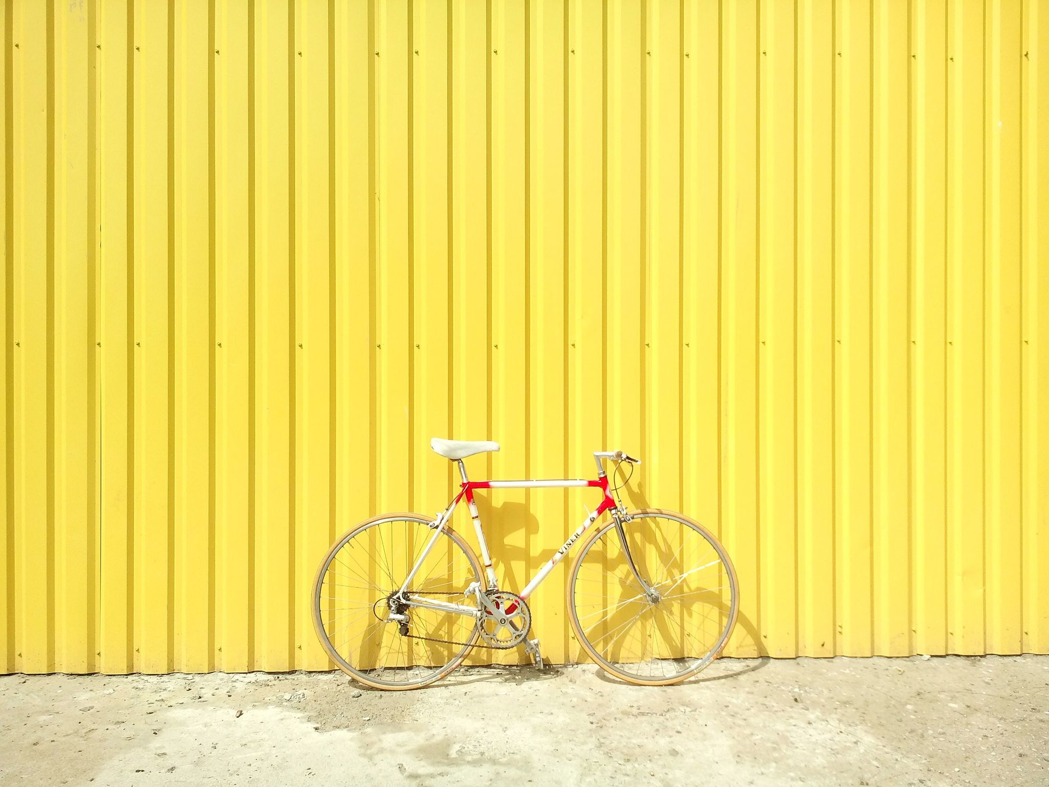 Bicycle, Yellow, Bicycle part, Wall, Bicycle wheel, Vehicle, Line, Bicycle handlebar, Bicycle accessory, Bicycle frame, 