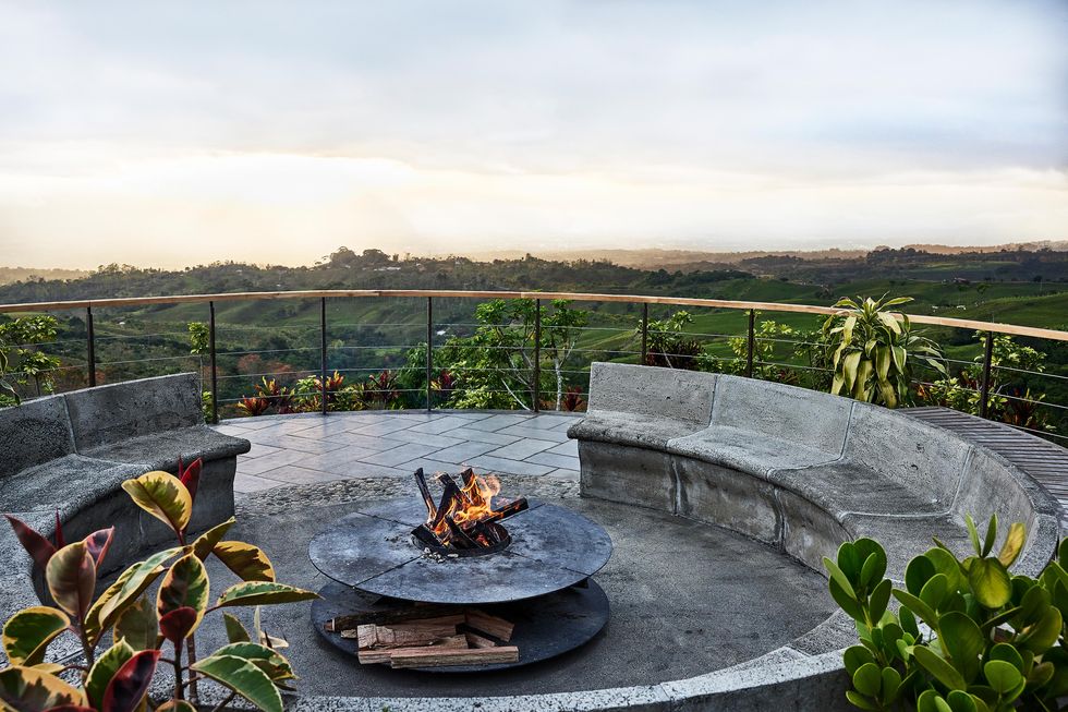 a fire pit with a fire pit and a fence and trees in the background