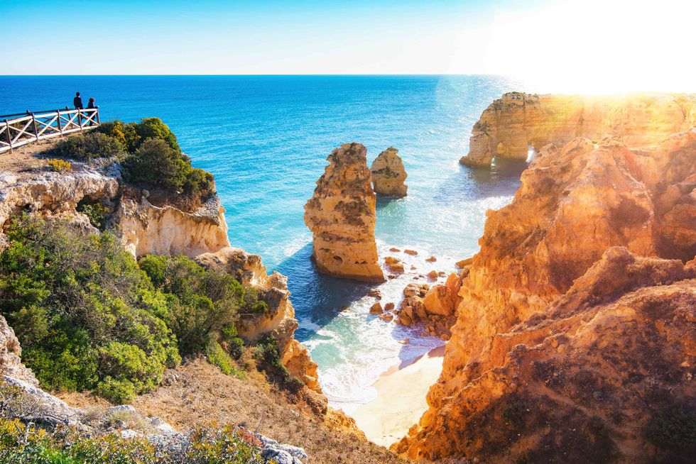 praia da marinha, one of the most beautiful beaches of portugal, algarve, was named by michelin guide to be one of the 10 most beautiful beaches in europethis photo captures the setting sun above one of the few natural arches near the beach