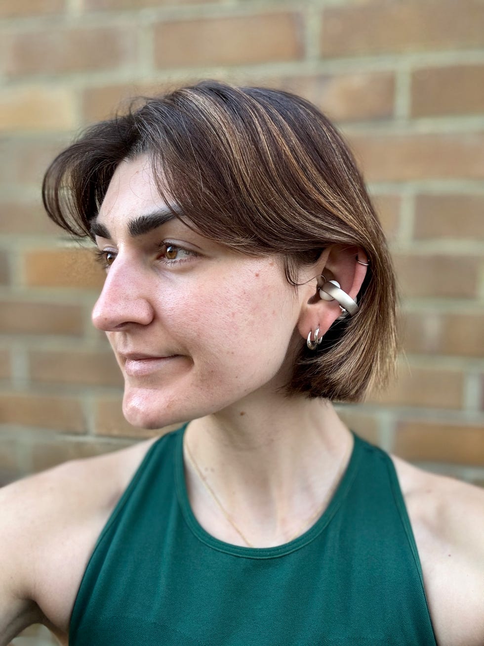a woman wearing a pair of cuff style earbuds