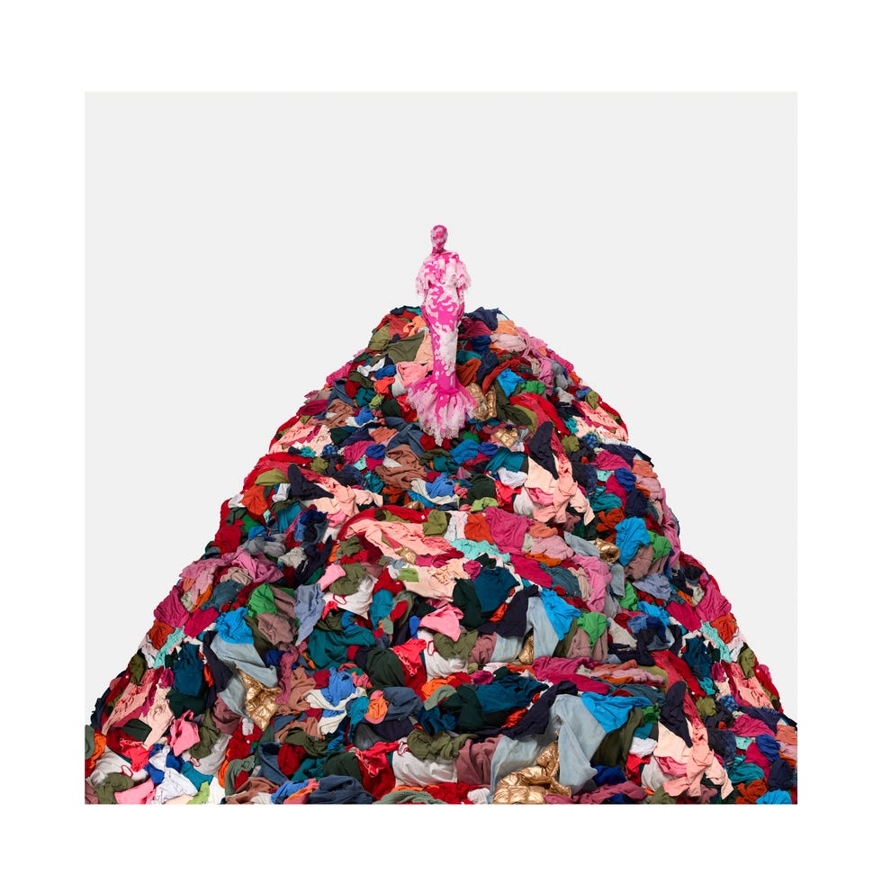 woman in pink dress atop a mountain of clothing