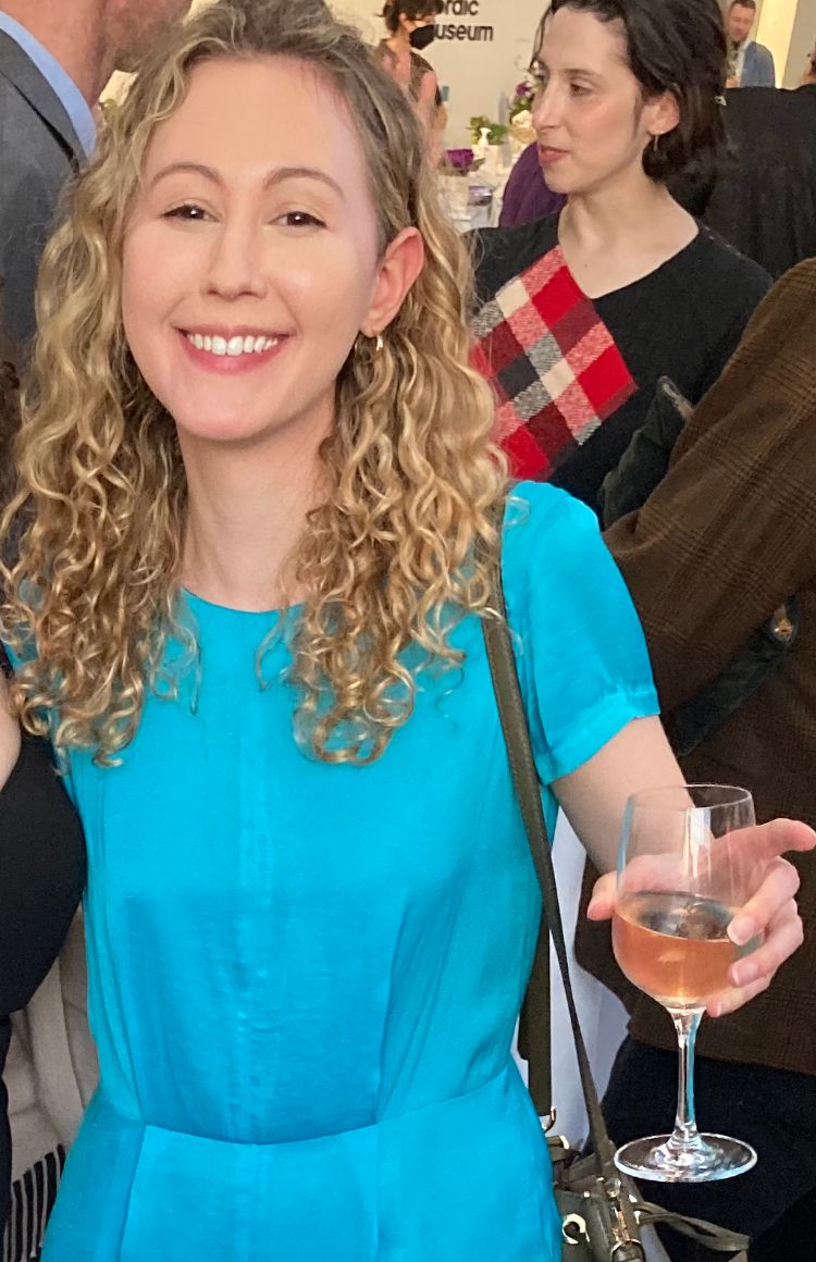 a woman smiling and holding a glass of wine