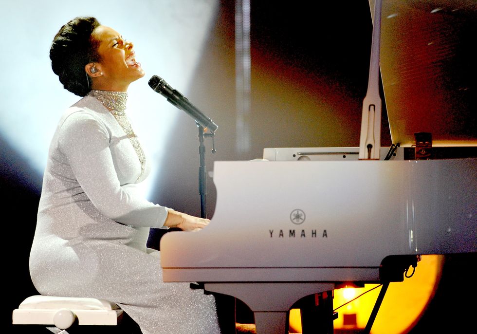 alicia keys singing into a microphone and playing a white piano