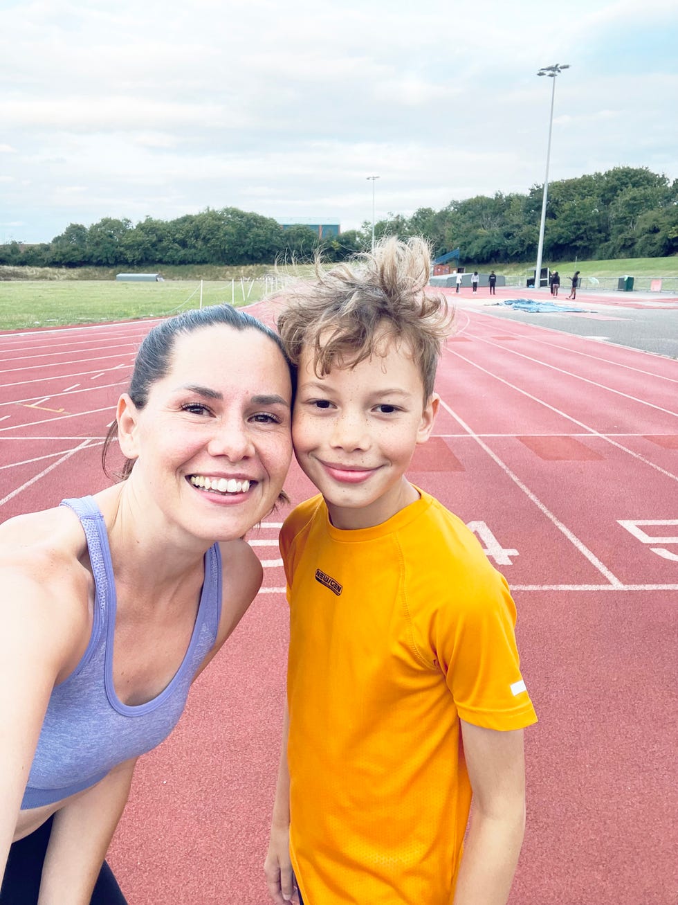 two individuals posing for a selfie on a running track