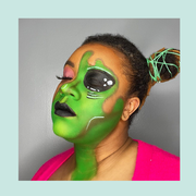 person on the left with two buns and green alien makeup over half their face and a person on the right with blue full body alien makeup and rosy cheeks