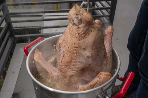 lowering the turkey into the hot oil