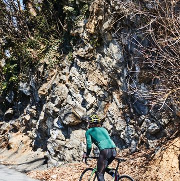 a person riding a bike on a road near a rocky cliff