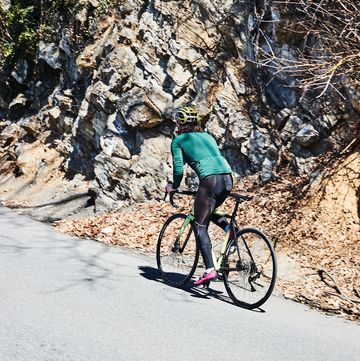 a person riding a bike on a road near a rocky cliff