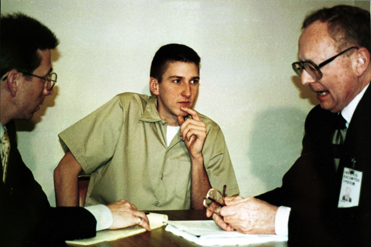 timothy mcveigh, wearing a tan prison jumpsuit, listening to two men in suits and glasses at a table