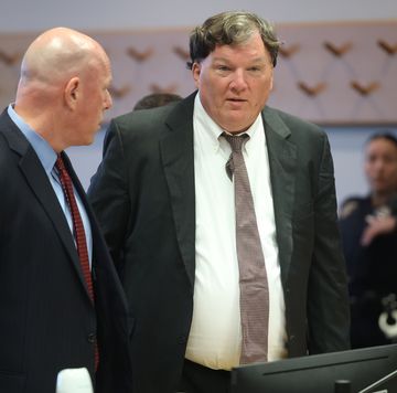 man standing behind a computer in a courtroom talking to another man