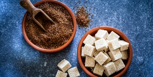 top view of two clay bowls filled with organic brown sugar from sugar cane and brown sugar cubes shot on abstract bluish background predominant colors are blue and brown low key dsrl studio photo taken with canon eos 5d mk ii and canon ef 100mm f28l macro is usm