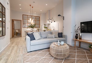 salón tipo loft con sofá gris, mesa de centro de fibras y alfombra de yute