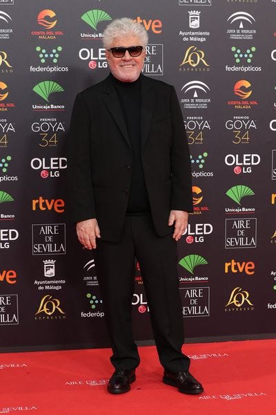 el director de cine pedro almodovar posando en un photocall vestido de negro y con gafas de sol