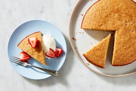 slice of almond cake on a blue plate with strawberries and whipped cream