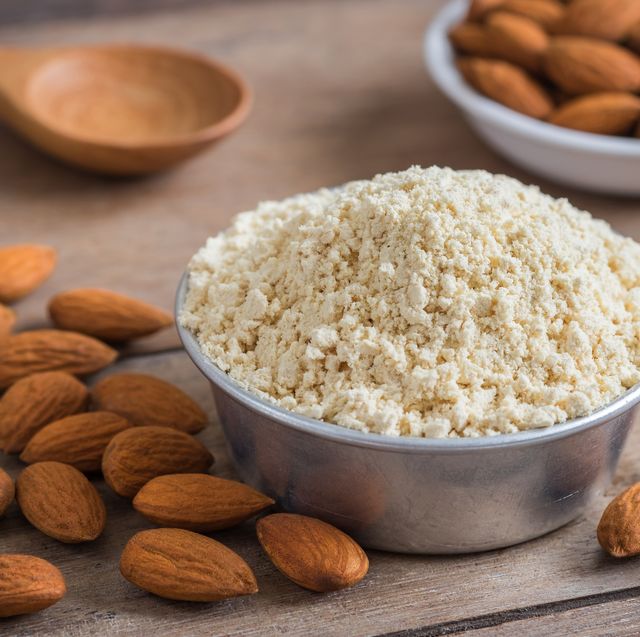 almond flour in bowl and almonds on wooden table